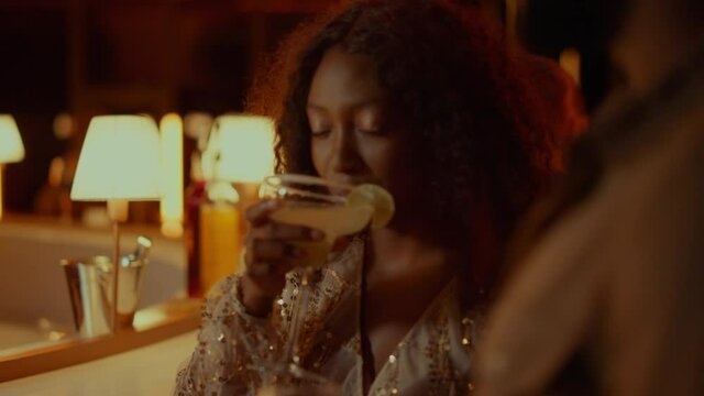 African american woman drinking cocktail in nightclub. Couple having rest in bar