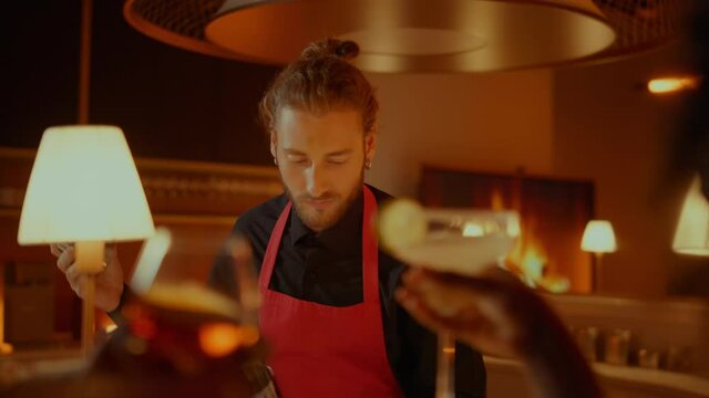 Handsome barman making cocktail in bar. Afro woman dancing in restaurant