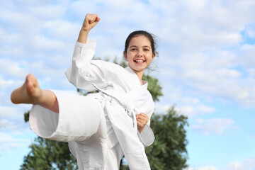Cute little girl in kimono training karate outdoors © New Africa