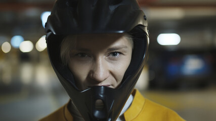 Naklejka na ściany i meble Portrait of young blonde woman with safety helmet in underground parking garage. High quality photo