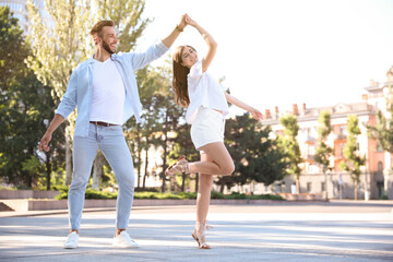 Lovely young couple dancing together outdoors on sunny day