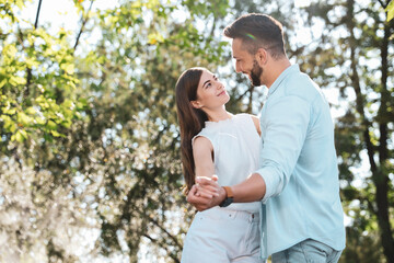 Obraz premium Lovely young couple dancing together in park on sunny day