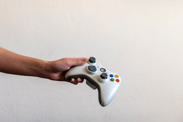 Una mano de mujer sujetando un mando inalámbrico blanco para jugar a video juegos