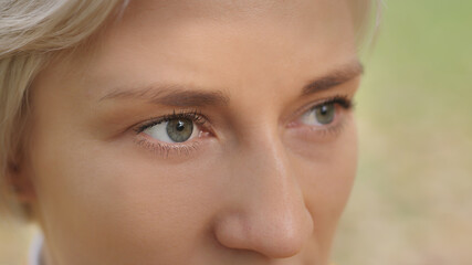 Close up. Green eyes of young caucasian blond woman in the park. High quality photo