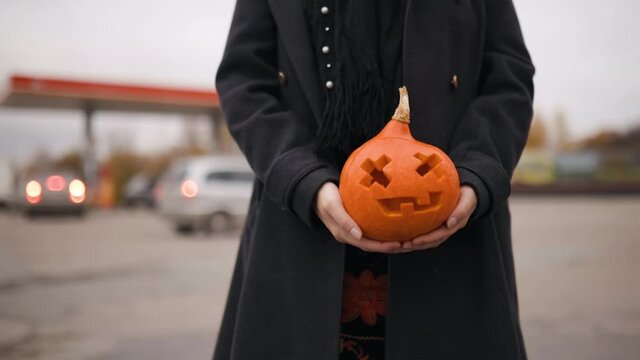 Carved pumpkin in female hands on Halloween eve