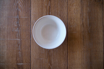 top view of an empty white Bowl on a wooden background