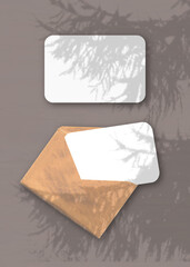 An envelope with two sheets of textured white paper on the brawn background of the table. Mockup...