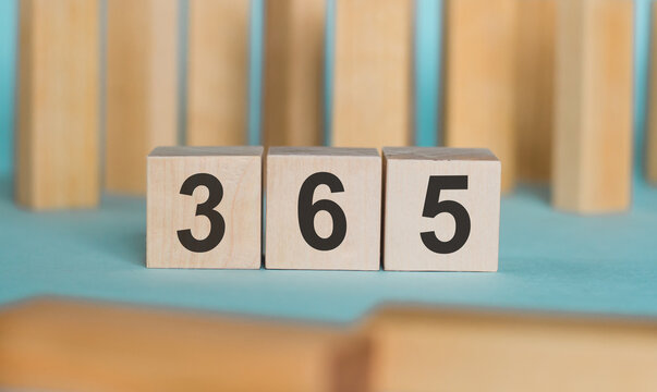 365 - word written on wooden blocks on light blue background.