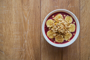 Top view of Brazilian açaí Bowl with bananas and Granola with copy space