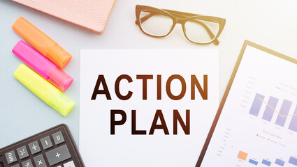 The text action plan on office desk with calculator, markers, glasses and financial charts.