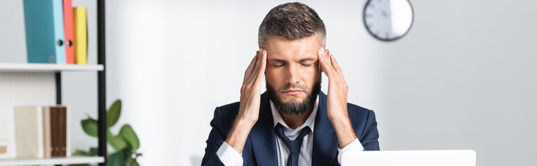 Businessman with closed eyes feeling headache while working in office, banner