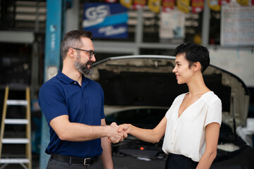 The mechanic shaking hands with customer after finish checking the car