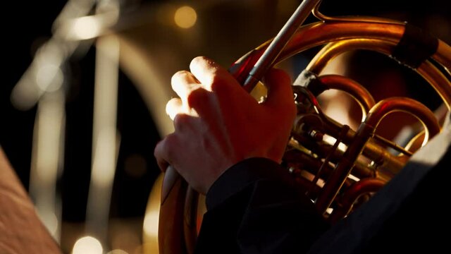 Close up of a man in orchestra playing french horn, 4k