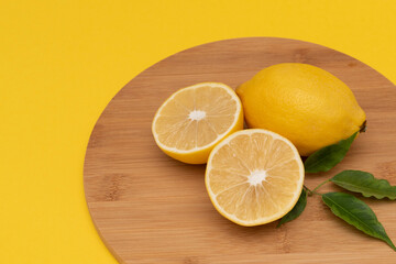 lemon on wooden round plank yellow background