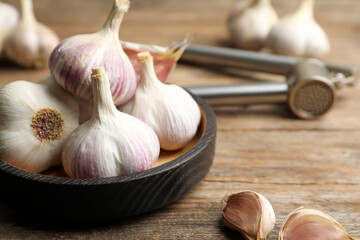 Fresh organic garlic in bowl on wooden table, closeup