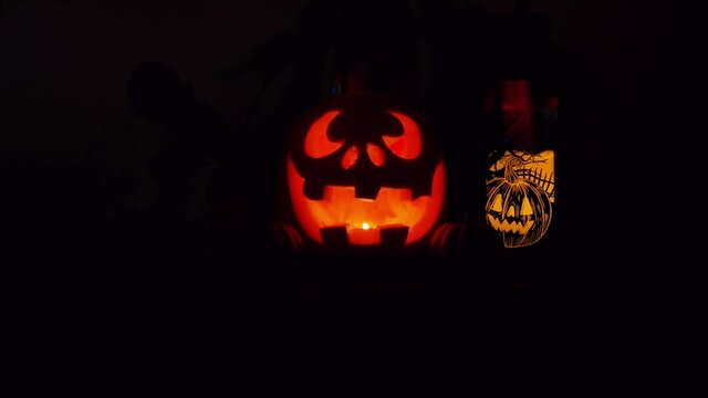 Halloween glowing pumpkins with black background. Orange glow light inside of carved pumpkin heads. Dark smile faces.