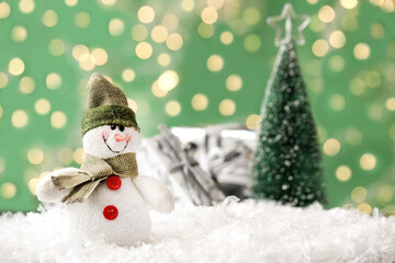 Snowman toy on snow against blurred festive lights, space for text. Christmas decoration