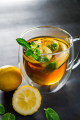 Tea with lemon and mint in transparent cup. Alternative medicine for treatment.