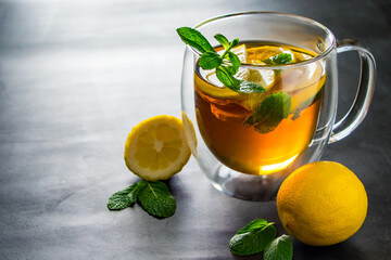 Tea with lemon and mint in transparent cup. Alternative medicine for treatment.
