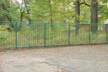 part of a green metal fence made of iron rods with a forged pattern