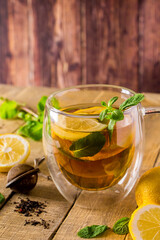 Herbal tea with lemon and mint on wooden background. Delicious drink for relaxation and alternative therapy of diseases.