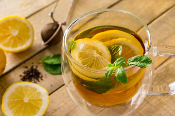 Herbal tea with lemon and mint on wooden background. Delicious drink for relaxation and alternative therapy of diseases.
