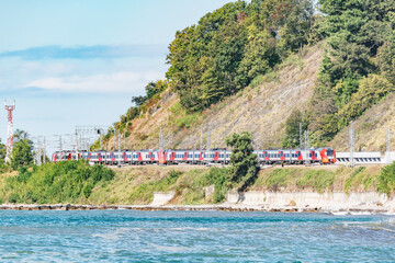 Passenger train moves along Black sea coast. Sochi.