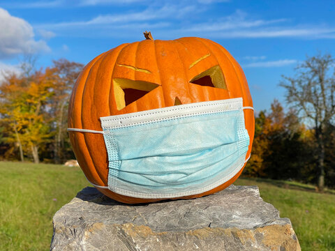 PORTRAIT: Big orange pumpkin decoration wearing a medical face mask on Halloween