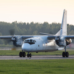 White old airplane is taxiing to take off on sunny day, rotating propeller/ old airplane with engines running and propeller on runway /Two propeller engine jet aircraft taxiing on the apron