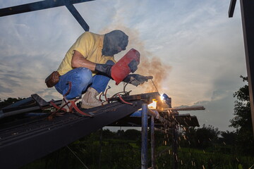 A technician uses a welding mask to work on a scaffold,Soft focus,selected focus,shallow depth of field.
