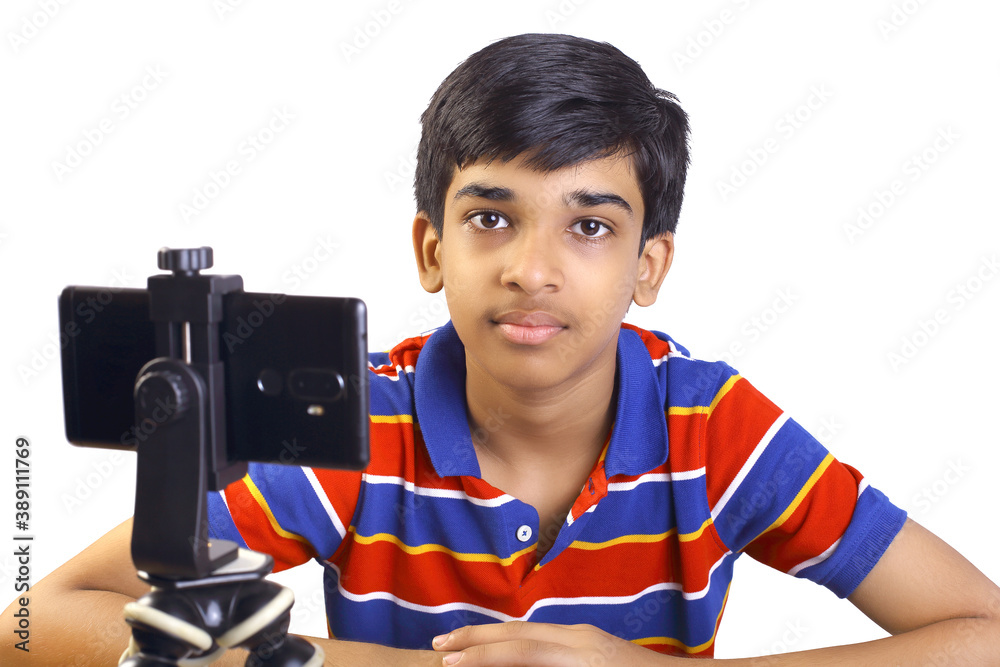 Wall mural Portrait of cute Indian boy using mobile phone while studying at home, remote education concept,