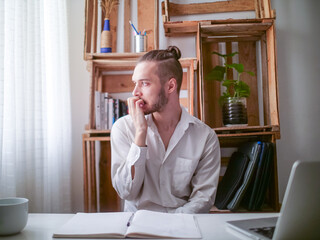 Young Caucasian Man in White Shirt Sitting at a Desk is Nervously Biting his Nails