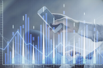 Double exposure of man's hands holding and using a digital device and forex graph drawing. Financial market concept.