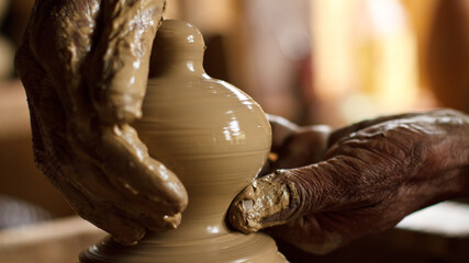 Potters hand, wheel throwing a red clay pot
