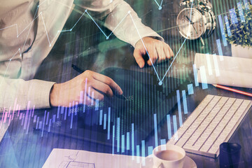 Double exposure of man's hands holding and using a phone and financial graph drawing. Analysis concept.
