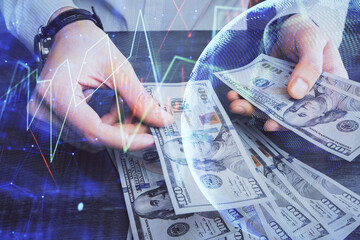 Multi exposure of financial graph drawing hologram and USA dollars bills and man hands. Analysis concept.