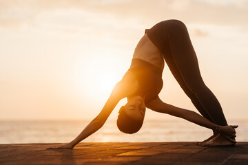 Yoga at sunset on the beach. woman performing asanas and enjoying life on the ocean. Bali Indonesia.