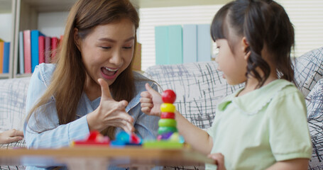 Cheerful family playing with wooden educational toy at home