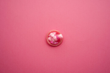 Condom week and valentines day concept with pink condom and heart shape beads and blank puzzle Men protection erection latex wrapped