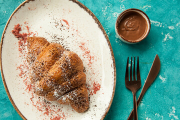 freshly baked croissant with an interesting presentation.
fragrant crispy croissant for breakfast, blue background, unusual serving of the dish