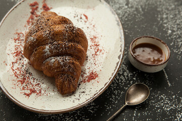 freshly baked croissant with chocolate topping.

fragrant crispy croissant for breakfast, dark background, unusual serving of the dish