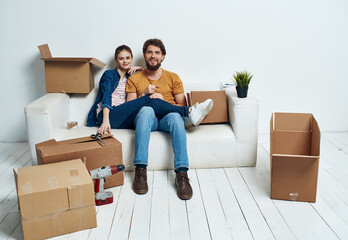 married couple in the apartment on the couch with boxes moving fun