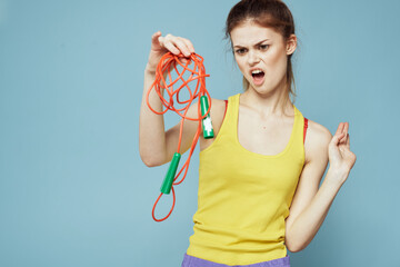 Woman with skipping rope sport exercise yellow tank top blue background