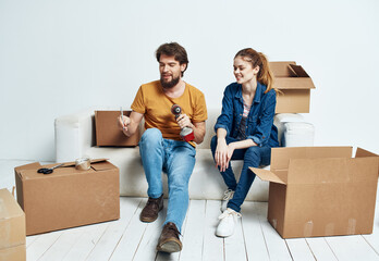 Man and woman are sitting on sofa with boxes of tools moving interior