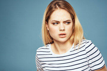 woman wearing striped t-shirt cropped view blue isolated background displeased facial expression