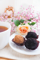 three candies on a saucer, a cup of tea and flowers. Life style..