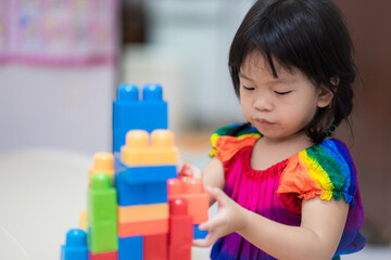 Young girl play with colorful plastic blocks. Asian child learn shapes and imagination. Concept of hand muscle development. Children aged 3 years 8 months.