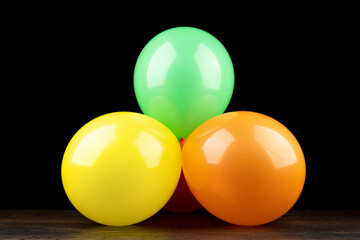 Bunch of colorful balloons on a wooden table against a black background.