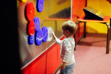 Toddler child plays with magnetic gears in the children's science amusement park, the child plays...