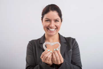 Caucasian woman holding two transparent heart-shaped aligners